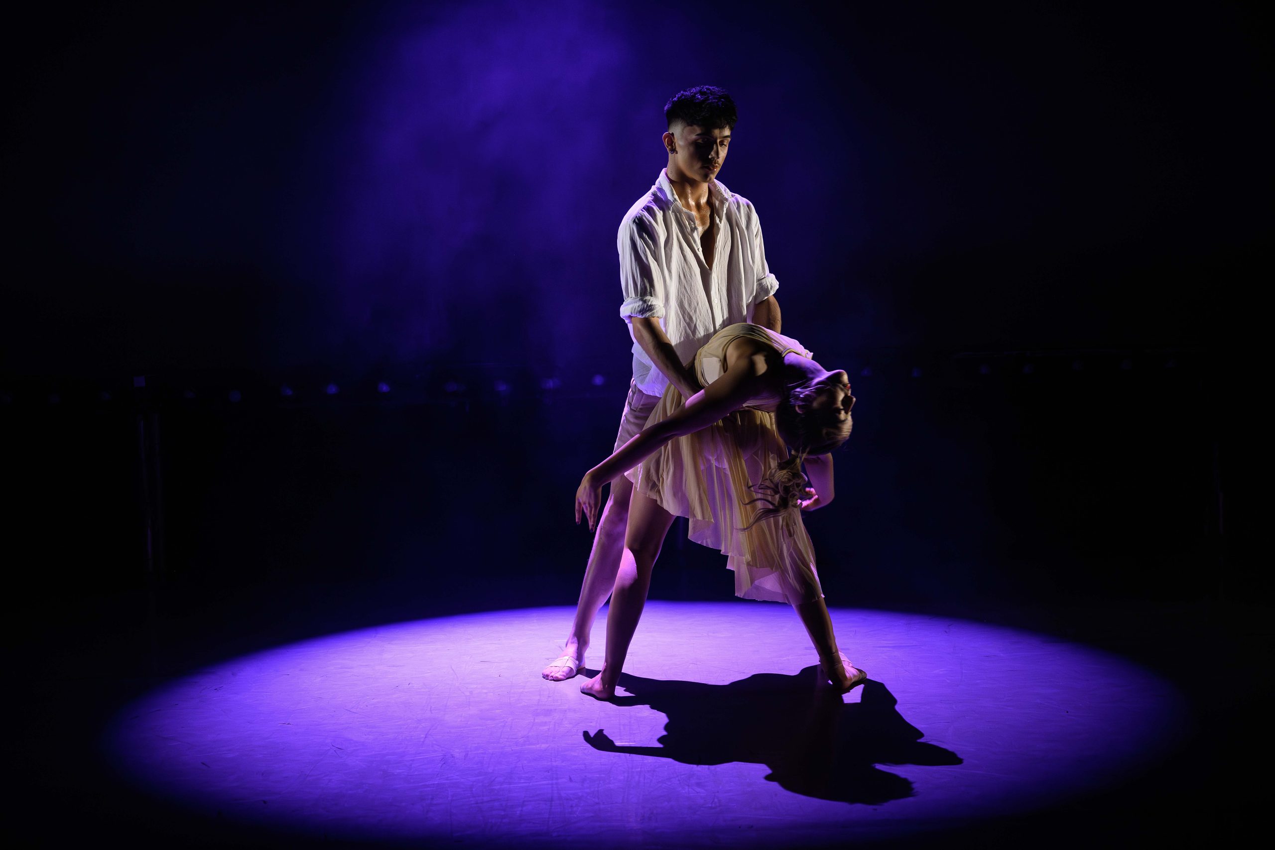 Two dancers striking a stunning pose lit by a blue spot light